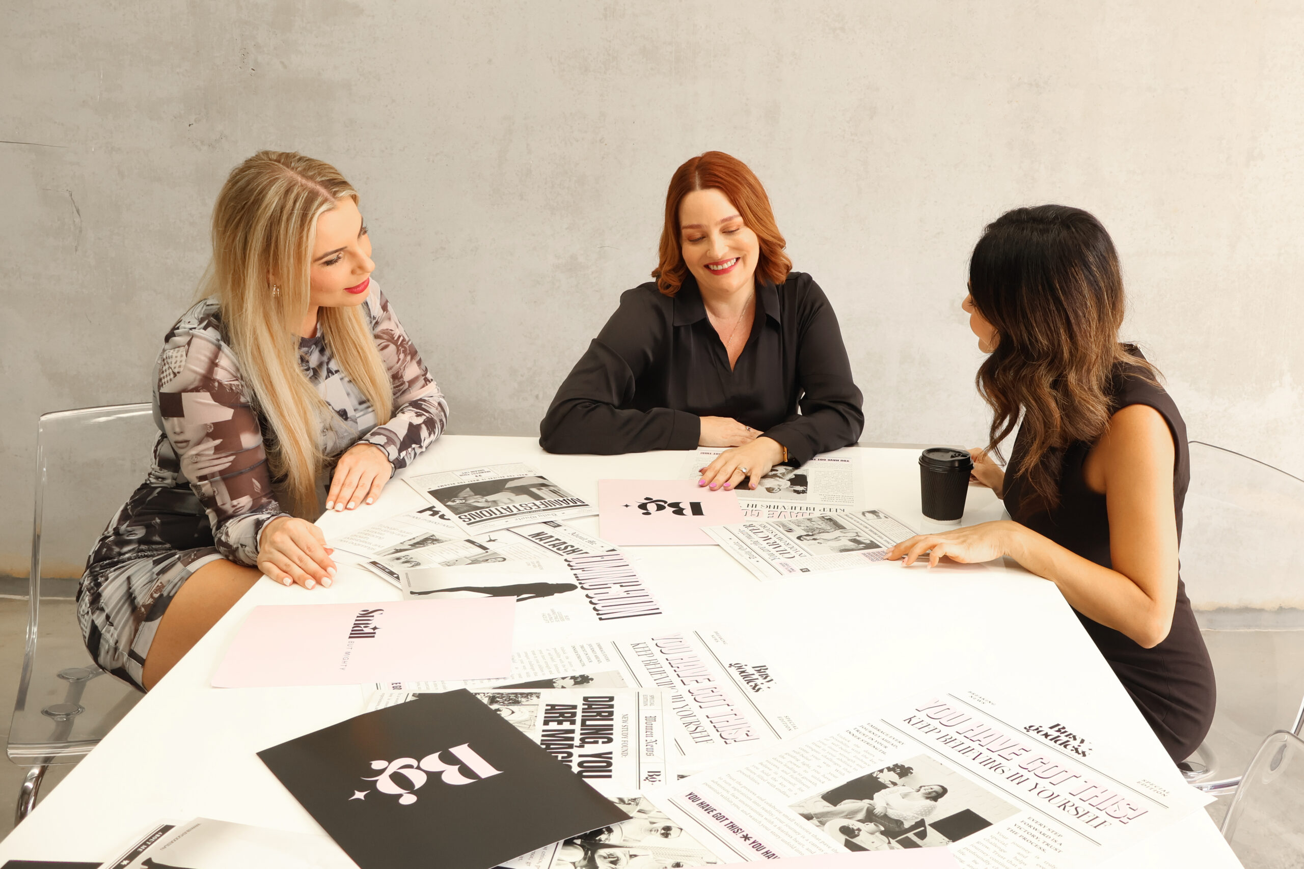 Natasha with Amy sitting reviewing concepts around white boardroom table